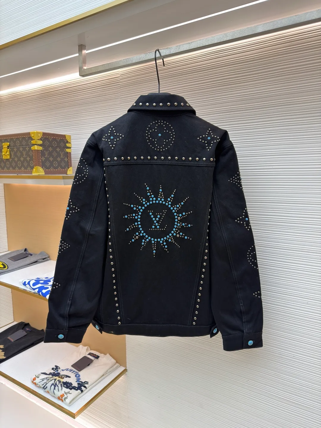 LOUIS VUITTON turquoise rivet denim jacket ●Original version: purchased and developed by 38979 ●Item number: 1682224-E30 ●Material: denim fabric ●Technology: hand-made rivet inlay ●Color: black ●Version: fitted version ●Weight: about 1550 grams ●Size: 46-48-50-52 ●Description: This black denim jacket is made of high-density twill denim fabric and has been treated with pre-washing water. It not only retains the crisp texture of the fabric, but also achieves a soft and skin-friendly wearing experience. The entire body of the garment is made of hand-made rivet inlay technology. The metal rivets are arranged at precise points to outline the outline of the brand's classic logo. Each rivet is manually hammered and fixed to ensure firmness and three-dimensionality. The placket and pockets are decorated with turquoise-textured resin buttons, which contrast with the metal rivets. The stitching on the collar, cuffs and hem adopts a double stitching process to enhance structural stability, while the edges are roughened to add a retro texture. The overall cut is a slightly loose Oversize version, combined with the three-dimensional tailoring process of the three-dimensional shoulder line, taking into account both styling and wearing comfort. Every detail is calibrated by hand, demonstrating the exquisite level of clothing making technology. The overall wiring is straight and delicate, the fabric is comfortable and soft, and the color is consistent without color difference. It can be matched with the same style to create a fashionable look and control various occasions. Customized accessories, complete with three standards, same style for men and women!